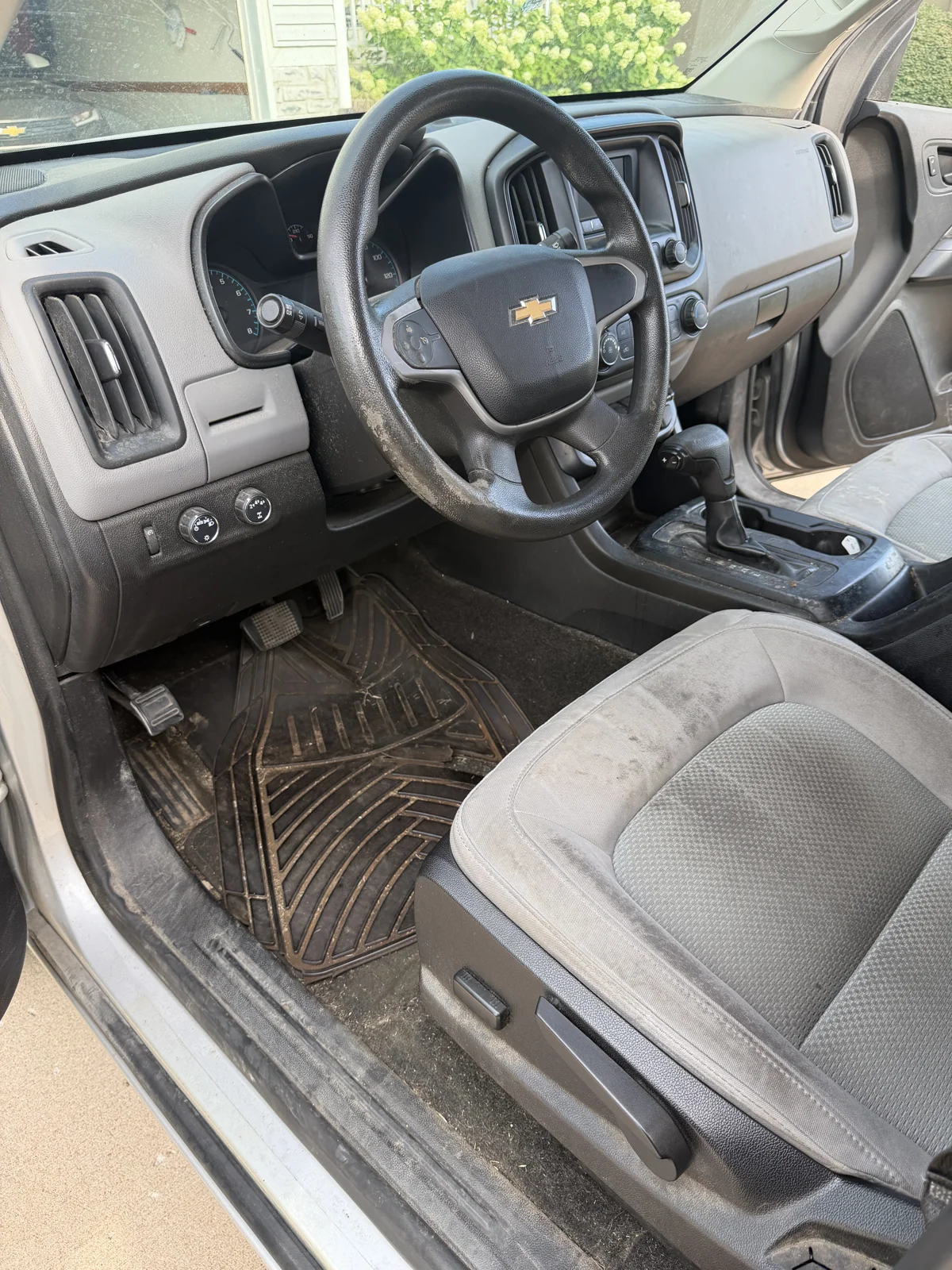 Pickup driver area before detailing with visible dirt on the mat, seat and steering wheel