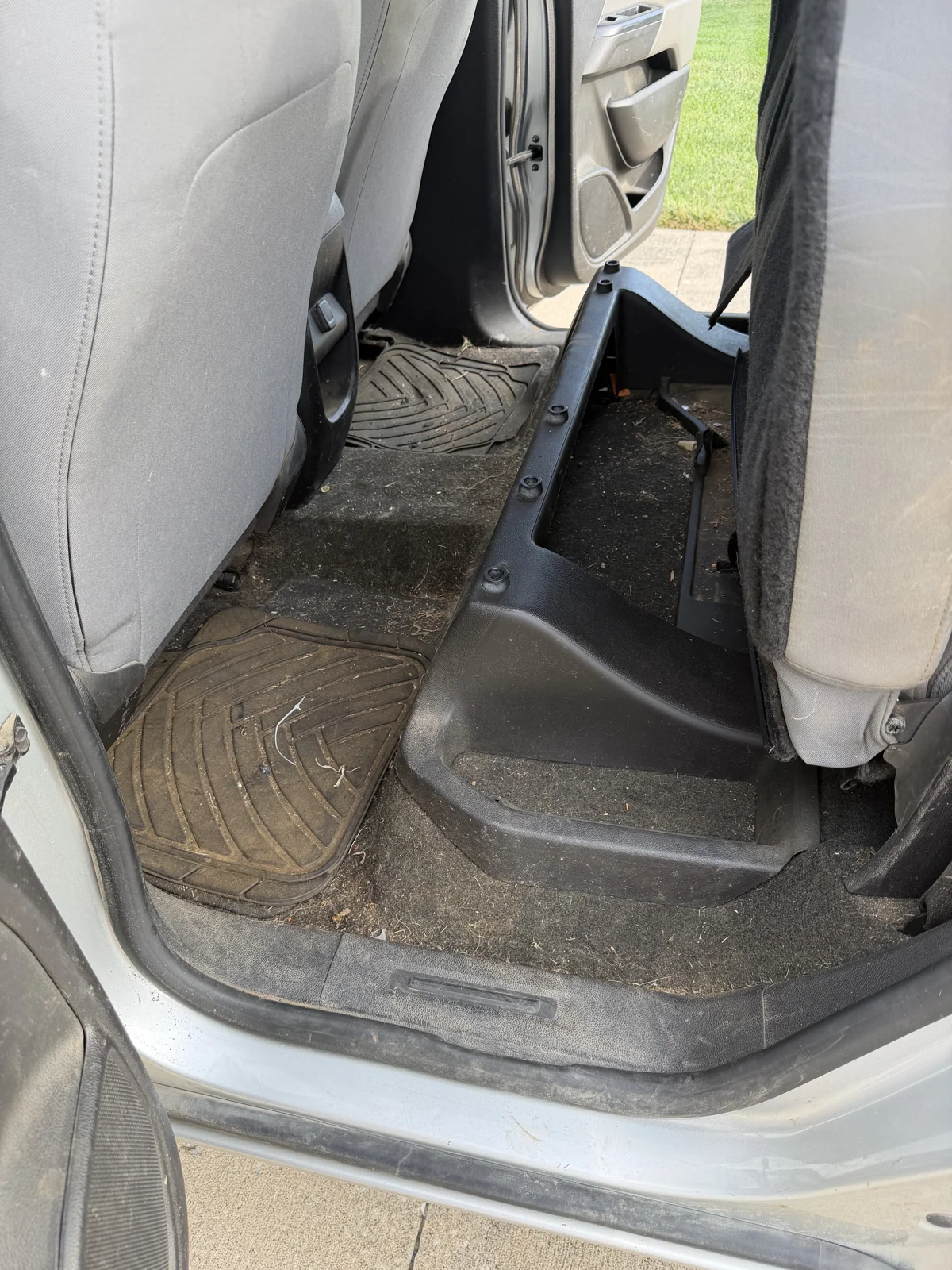 Rear pickup floor before detailing with dirt and debris around the seat bases